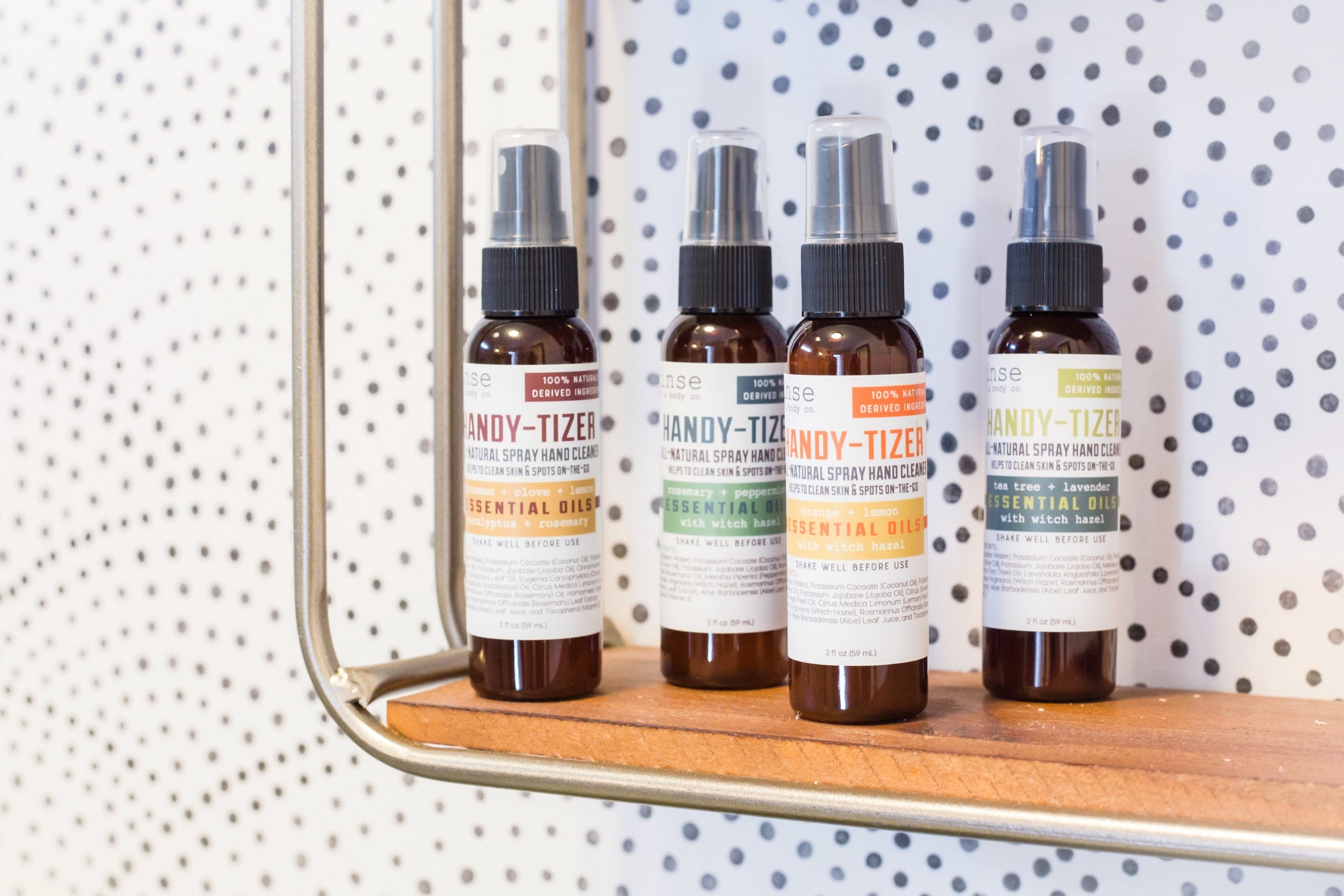 Handy-Tizer natural hand sanitizer sprays lined up on a wooden shelf - Rinse Bath & Body