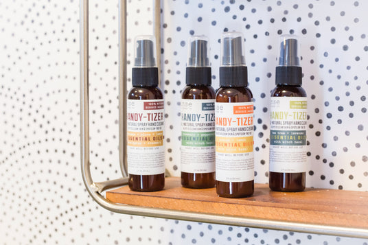 Handy-Tizer natural hand sanitizer sprays lined up on a wooden shelf - Rinse Bath & Body