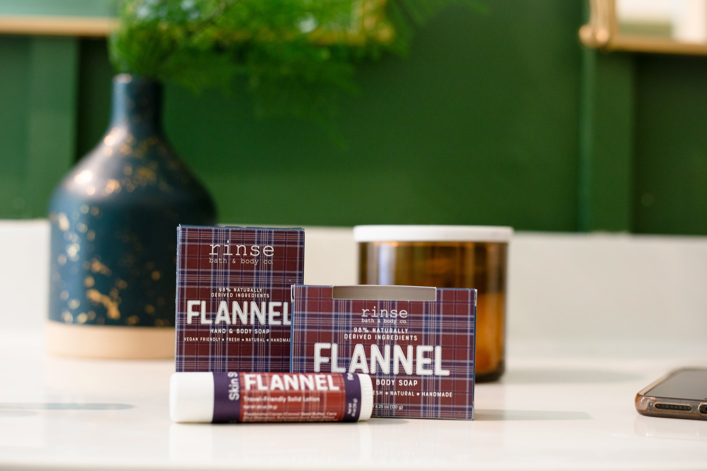 Rinse Flannel hand and body soap and candle styled on a shelf with a vase